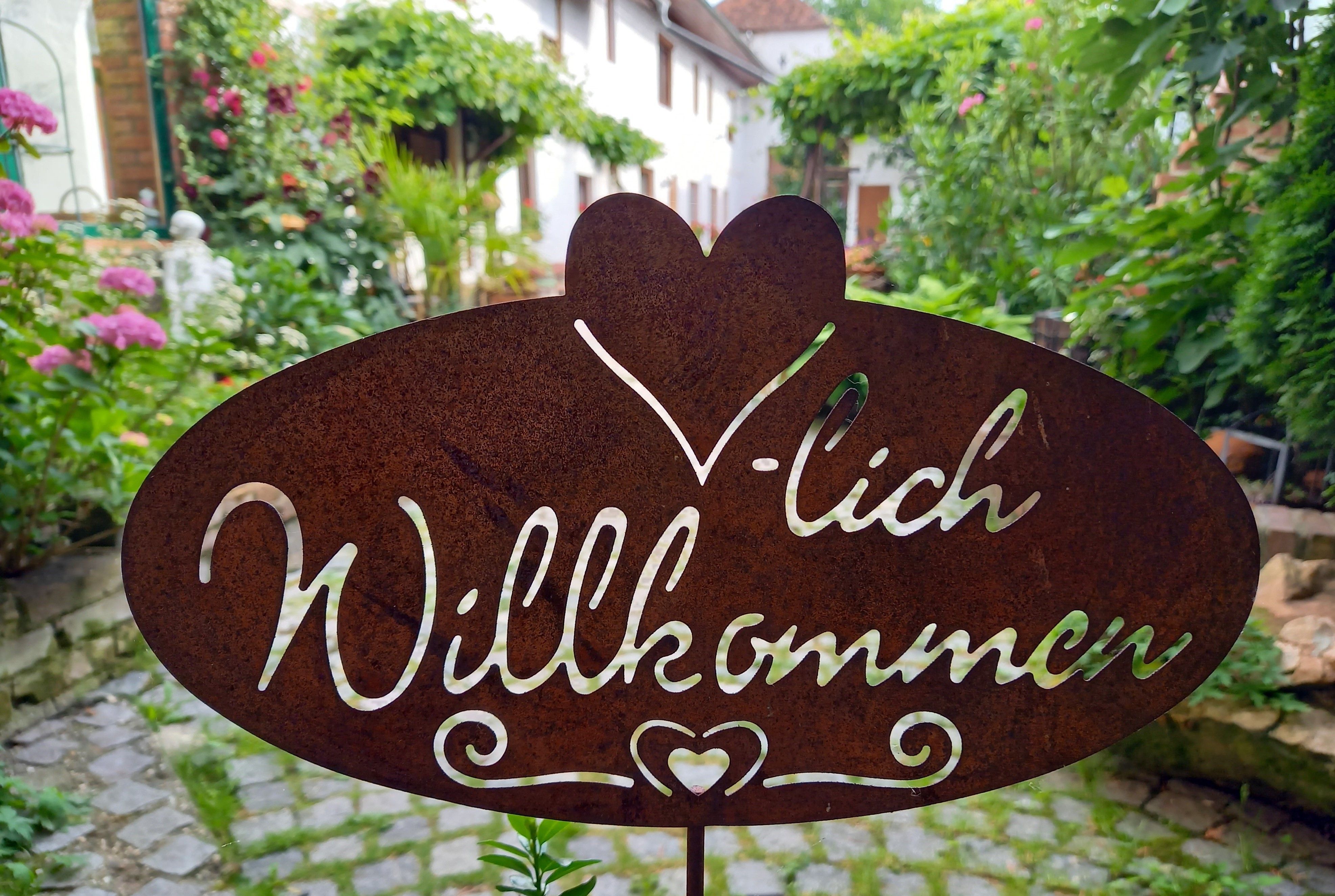 Metal sign with the inscription 'Welcome' in a garden.
