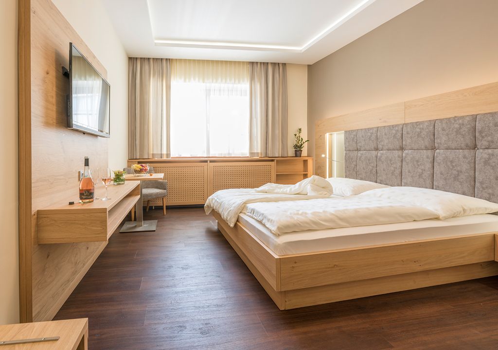 Modern guest room with double bed, flat screen TV and wooden furniture.