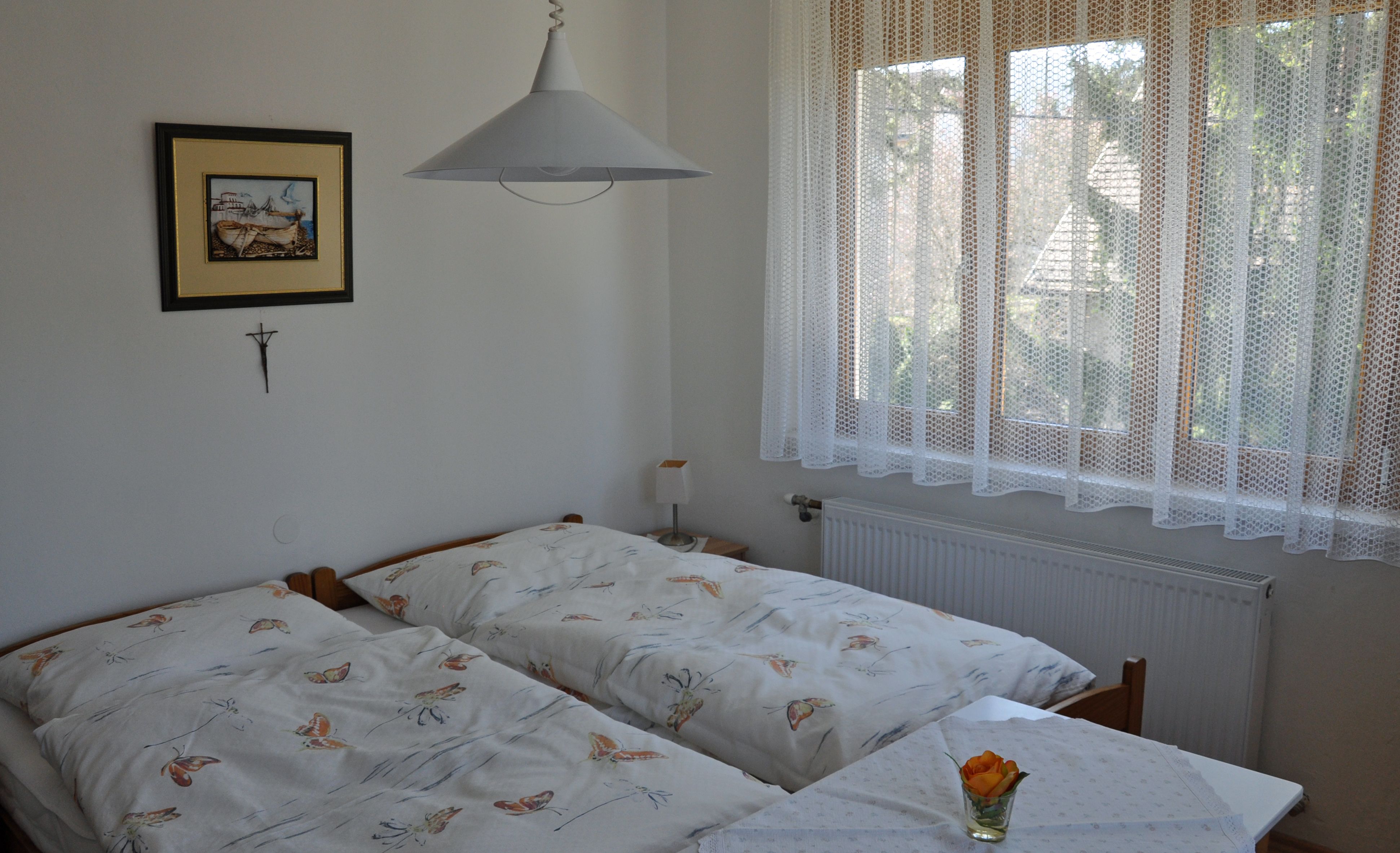 Cozy bedroom with two single beds, a picture on the wall and a window with a lace curtain.