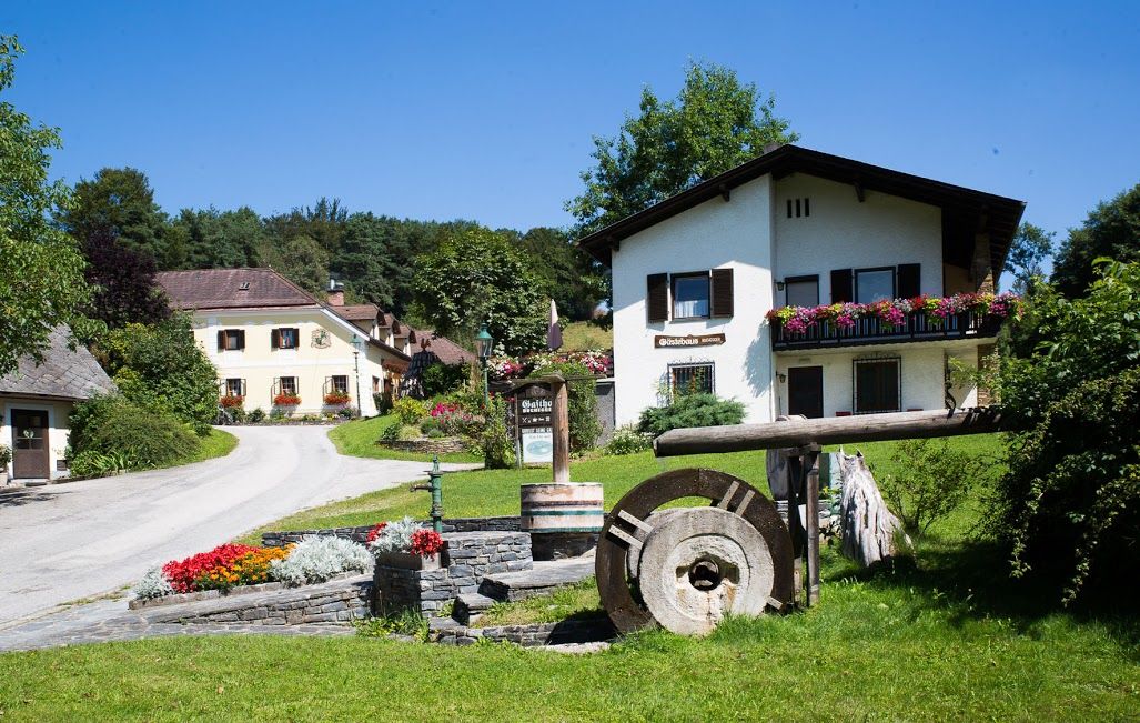 A rural guest house with flowers and an old millstone in the foreground.