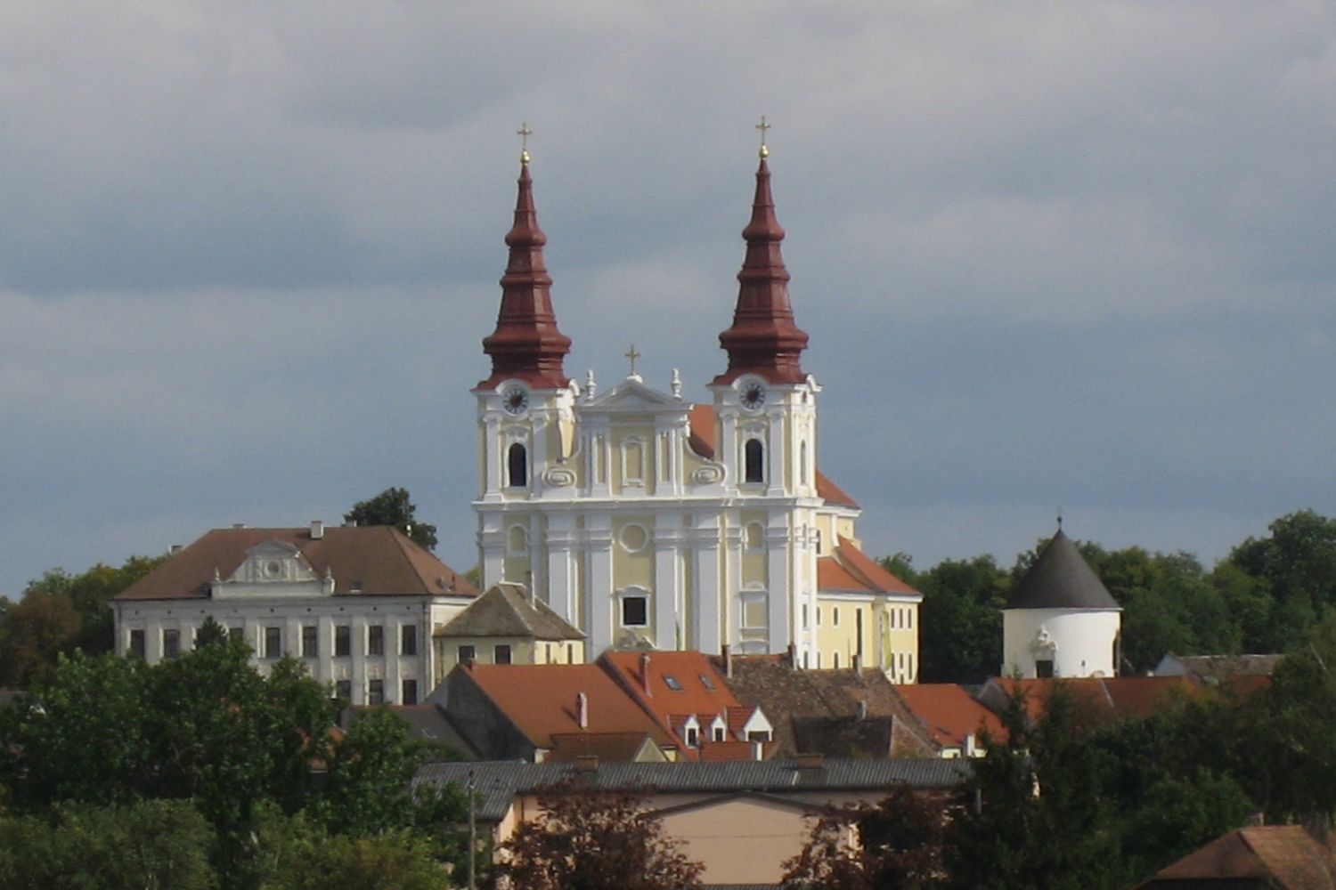 Baroque church with two towers and surrounding buildings.