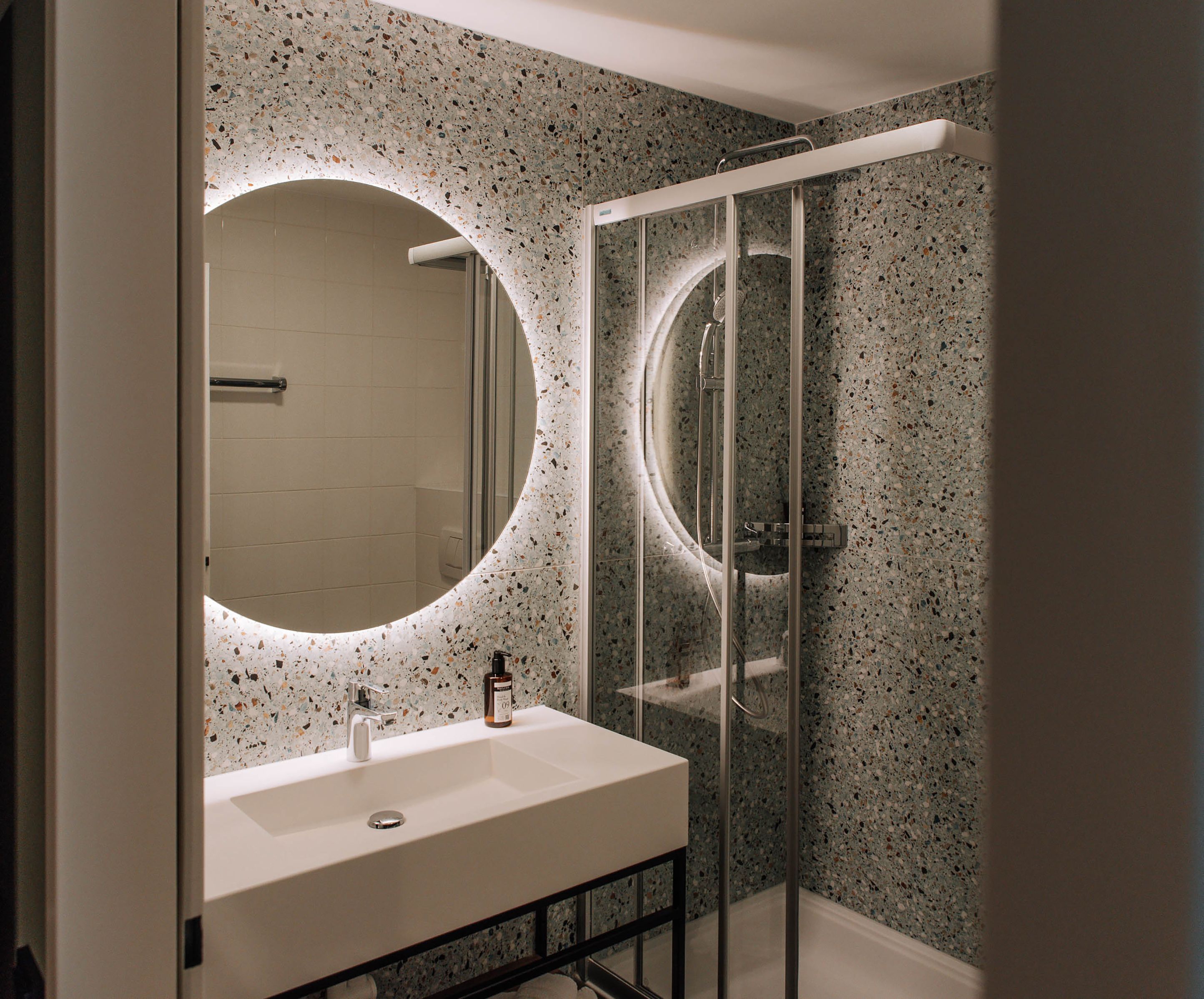 Modern bathroom with illuminated mirror and shower.