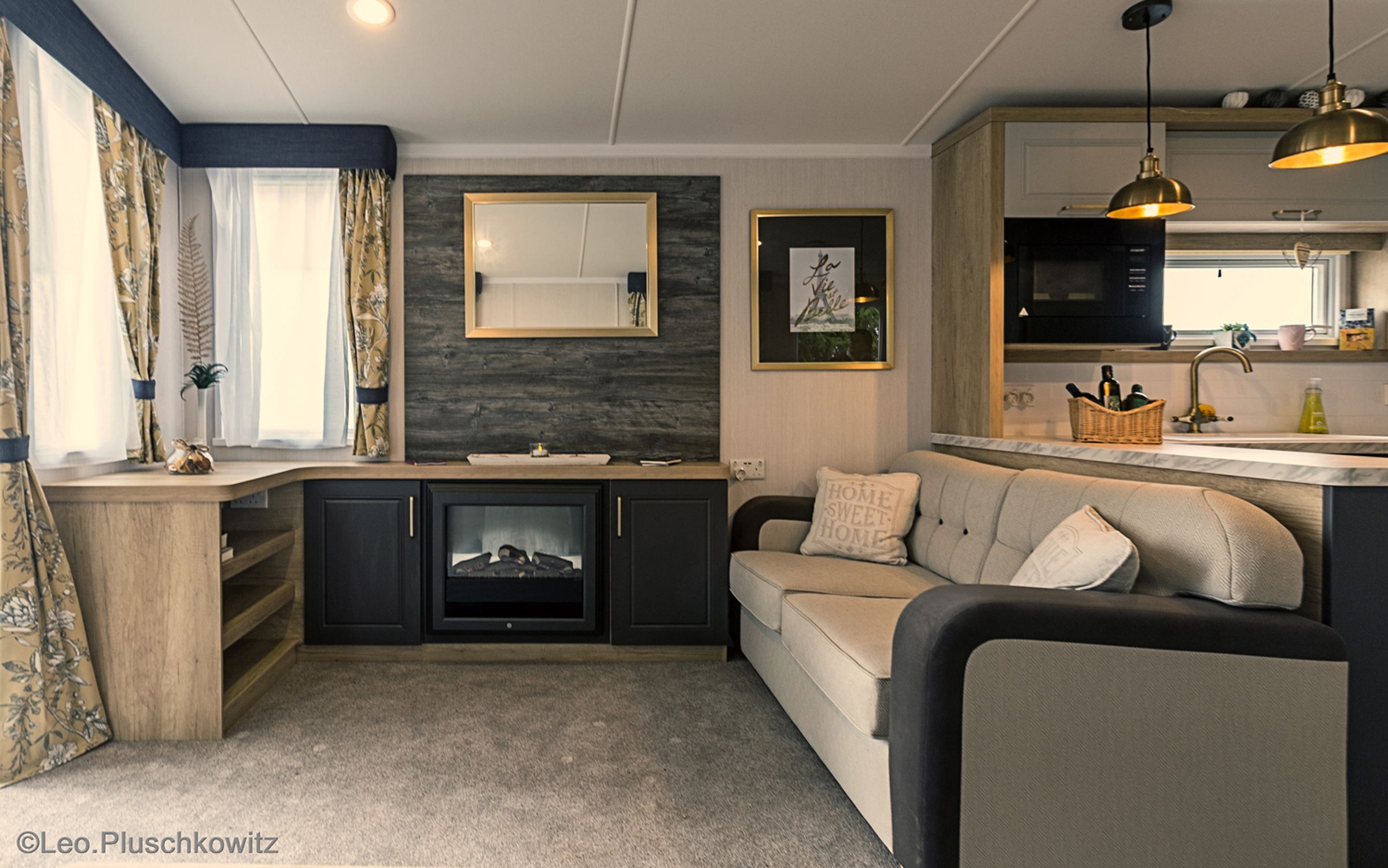 Cozy living room with sofa, fireplace, mirror and kitchen.