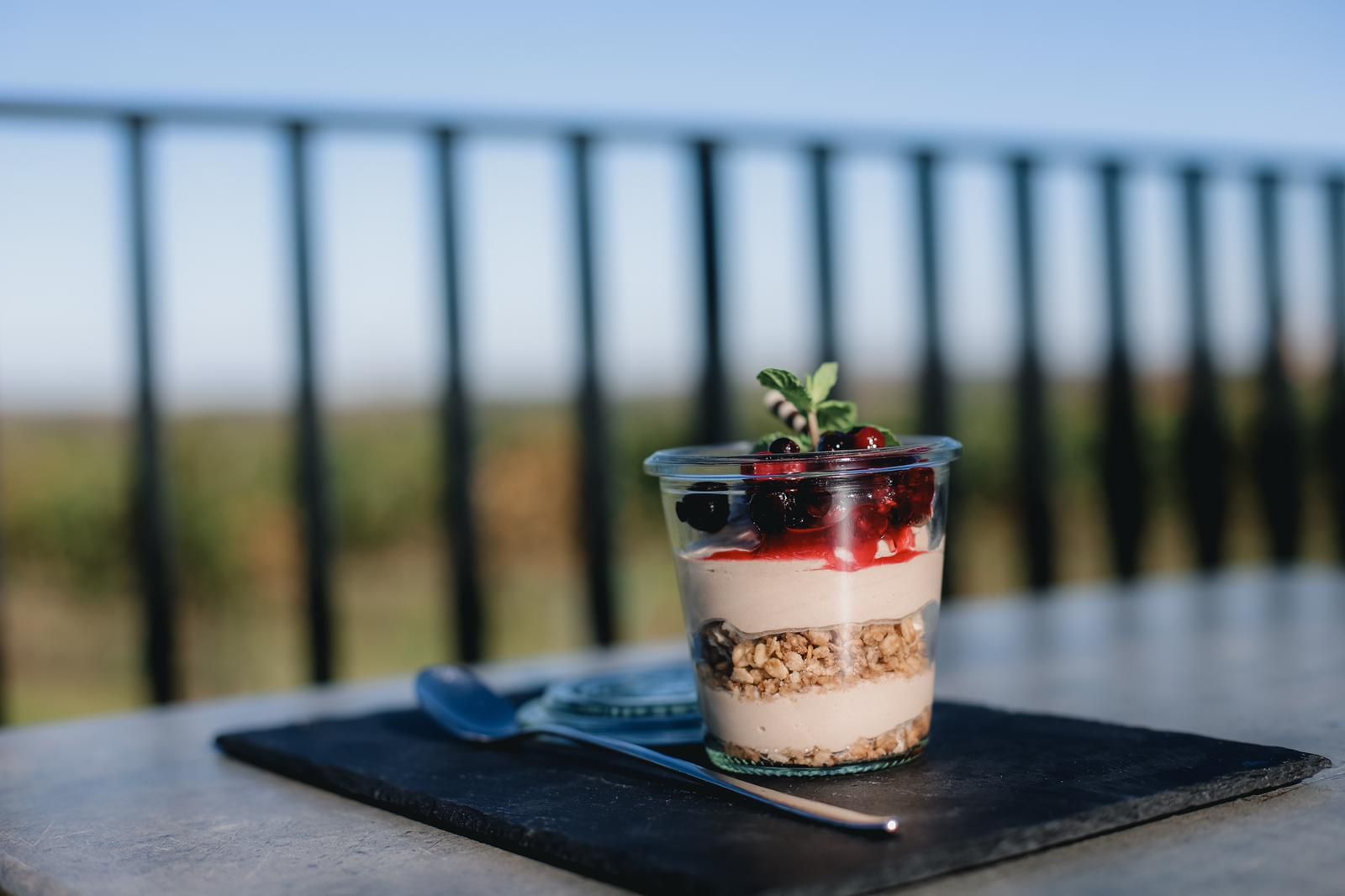 Dessert in a glass with berries and mint on a table with a blurred background.