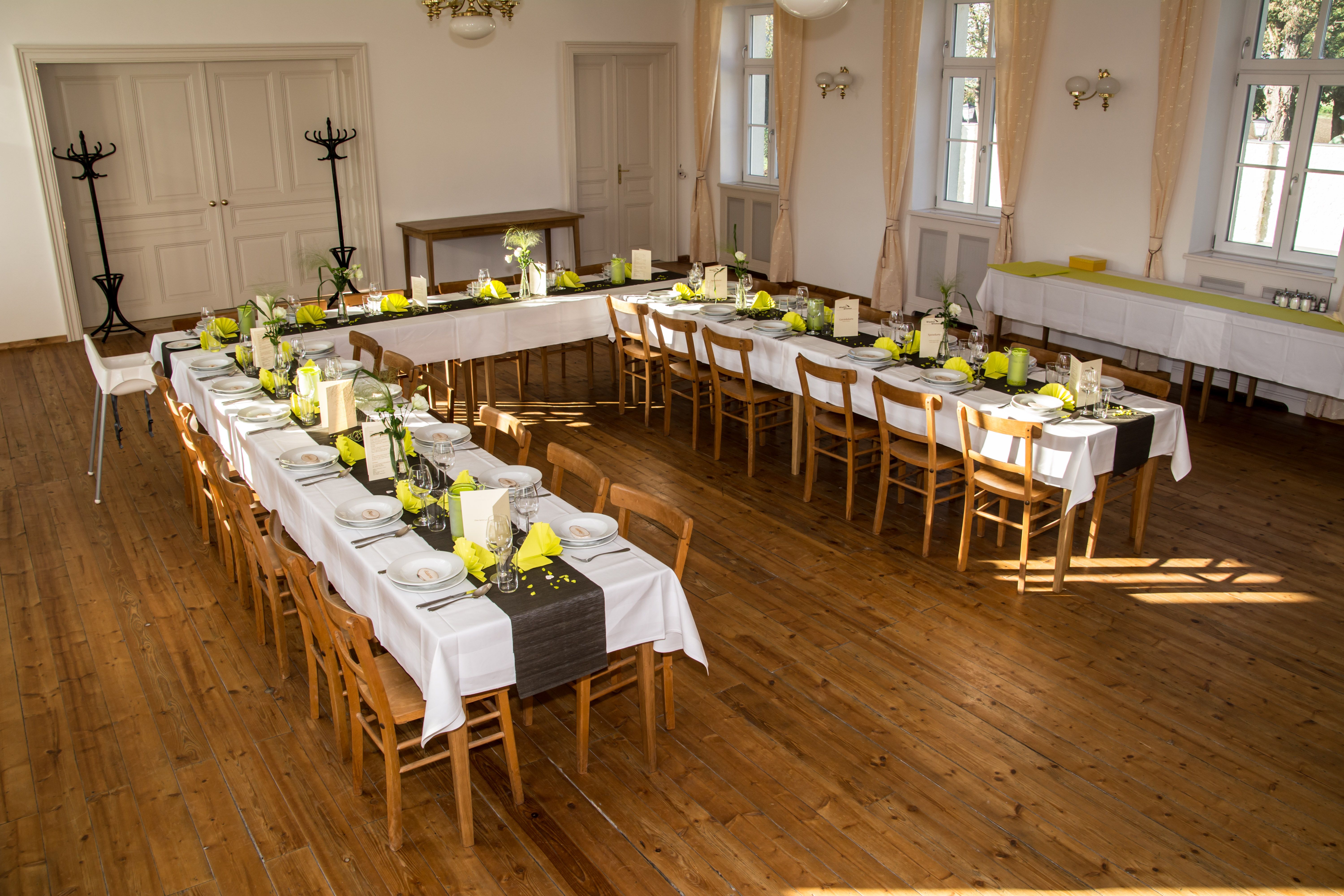 Festively decorated event hall with long tables and yellow napkins.