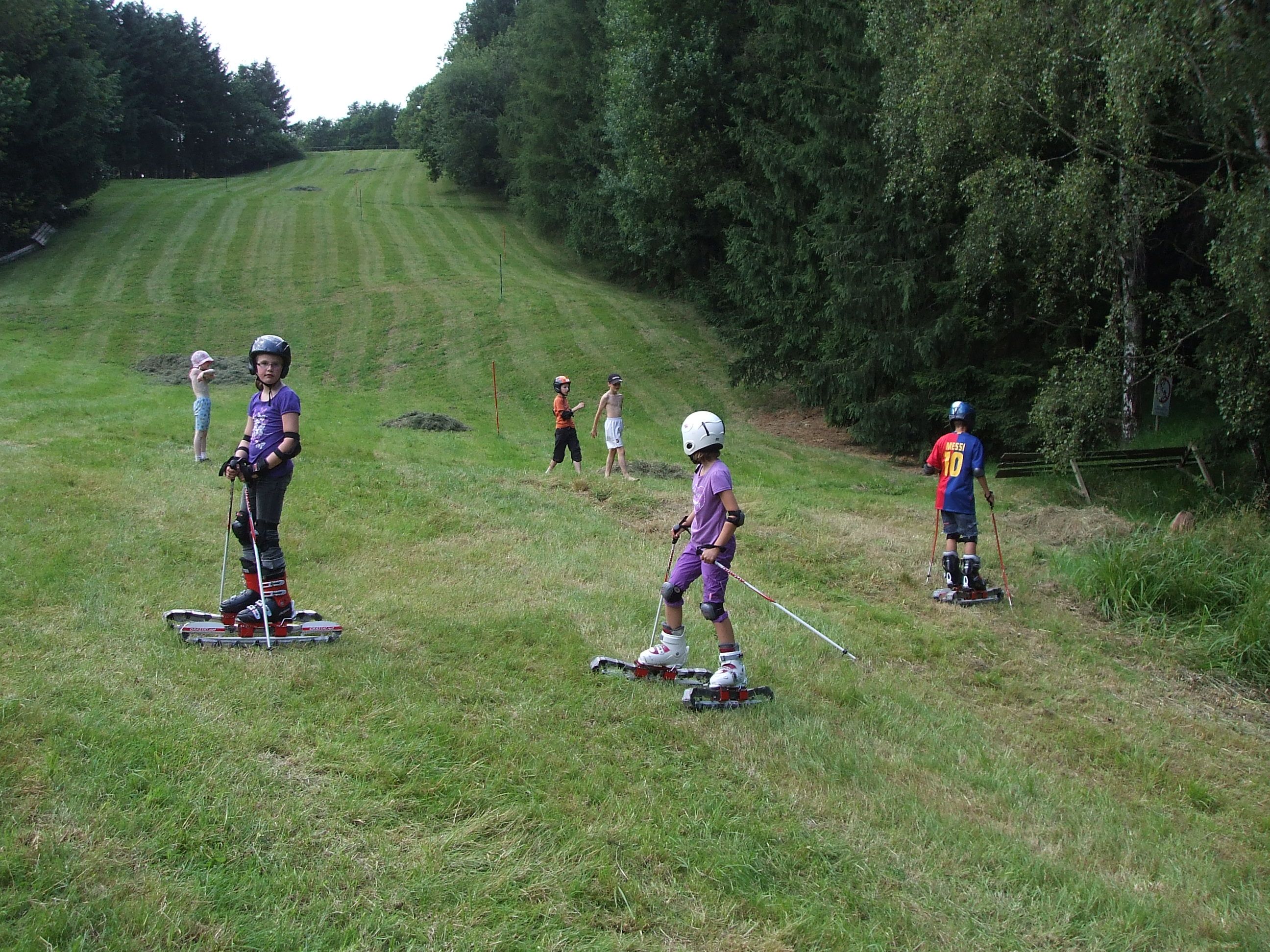 Children skiing with grass skis on a meadow.