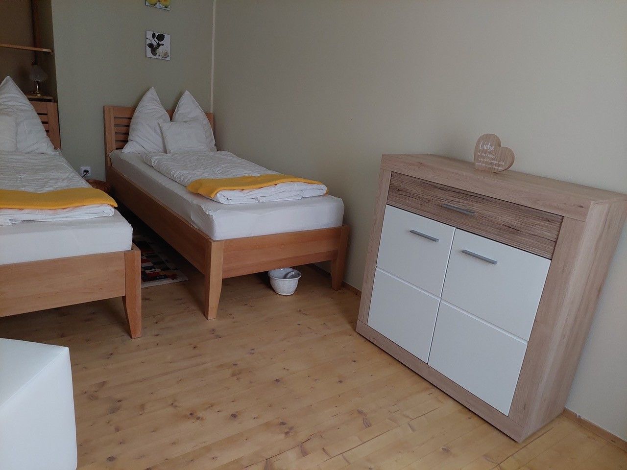 Twin room with two single beds, wooden floor and chest of drawers.