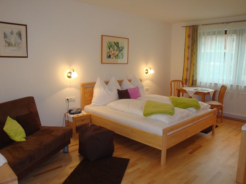 Comfortable hotel room with double bed, sofa and dining table.