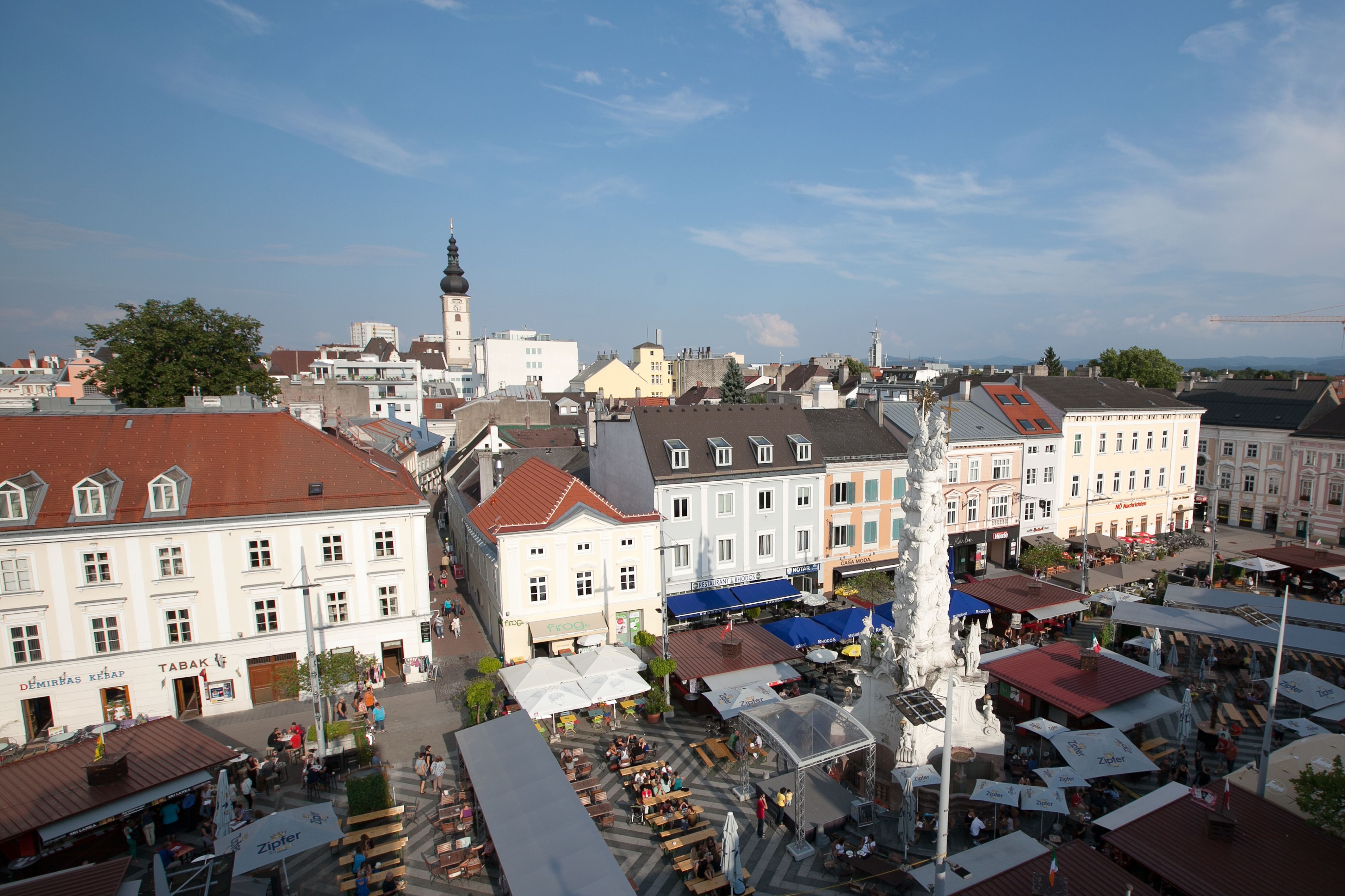 Aerial view of a busy square in St. Pölten with market stalls and a tower in the background.