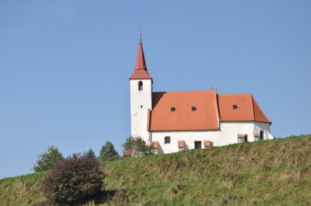Ofenbach parish church on a hill with a blue sky in the background.