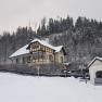 Wintery Villa Waldheimat with snow-covered roof and forest in the background.