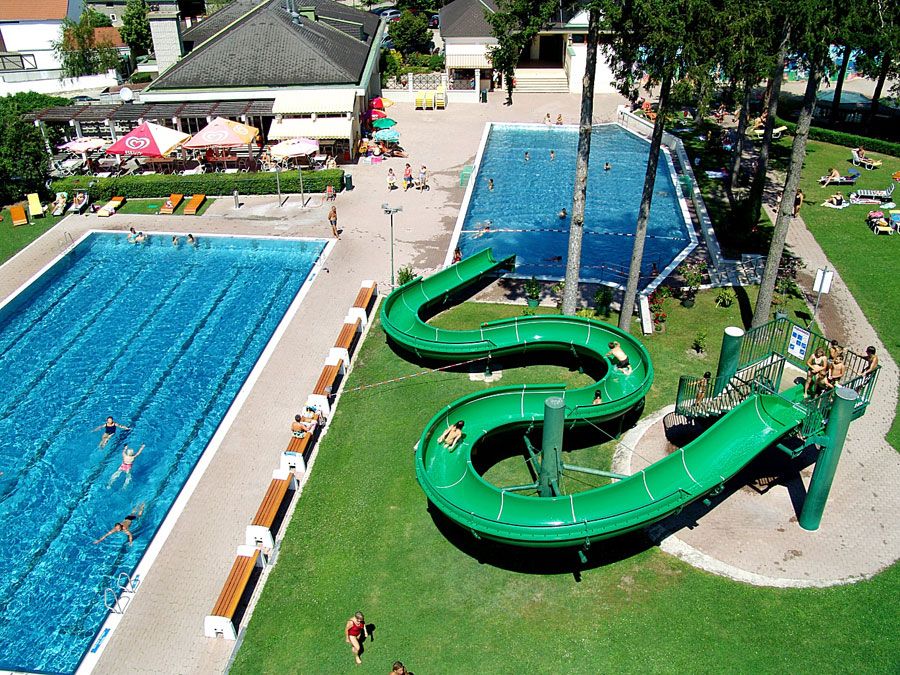 Aerial view of an outdoor pool with two pools and a green water slide.