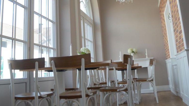 Elegant room with high windows, chandeliers and wooden furniture.