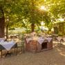 A sunny outdoor area of a restaurant with covered tables under trees.