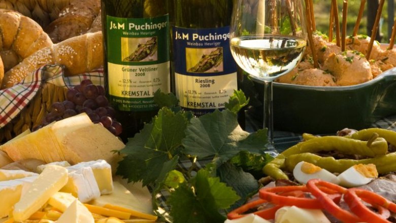 Heurigen snack with wine, cheese, bread and cold cuts on a table.