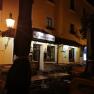 Night shot of a restaurant with the sign 'Adlerbräu' and empty tables outside.