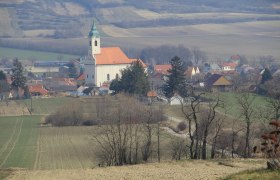 Landscape with church and village in the background, surrounded by fields and trees.