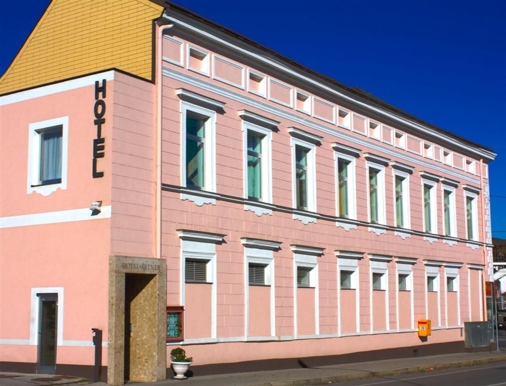 A pink building with the word 'Hotel' on the façade.