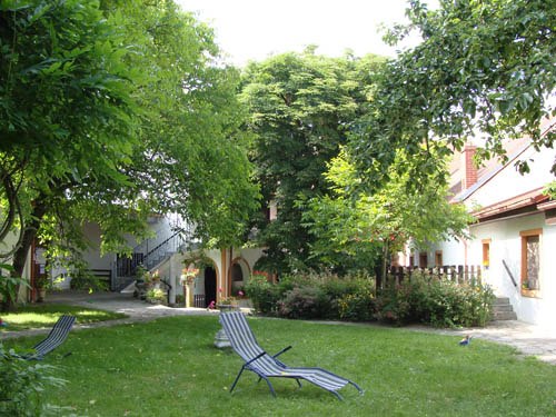 A green inner courtyard with sun loungers and trees, surrounded by buildings.