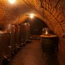 A wine cellar with metal tanks and a barrel, illuminated by warm light.