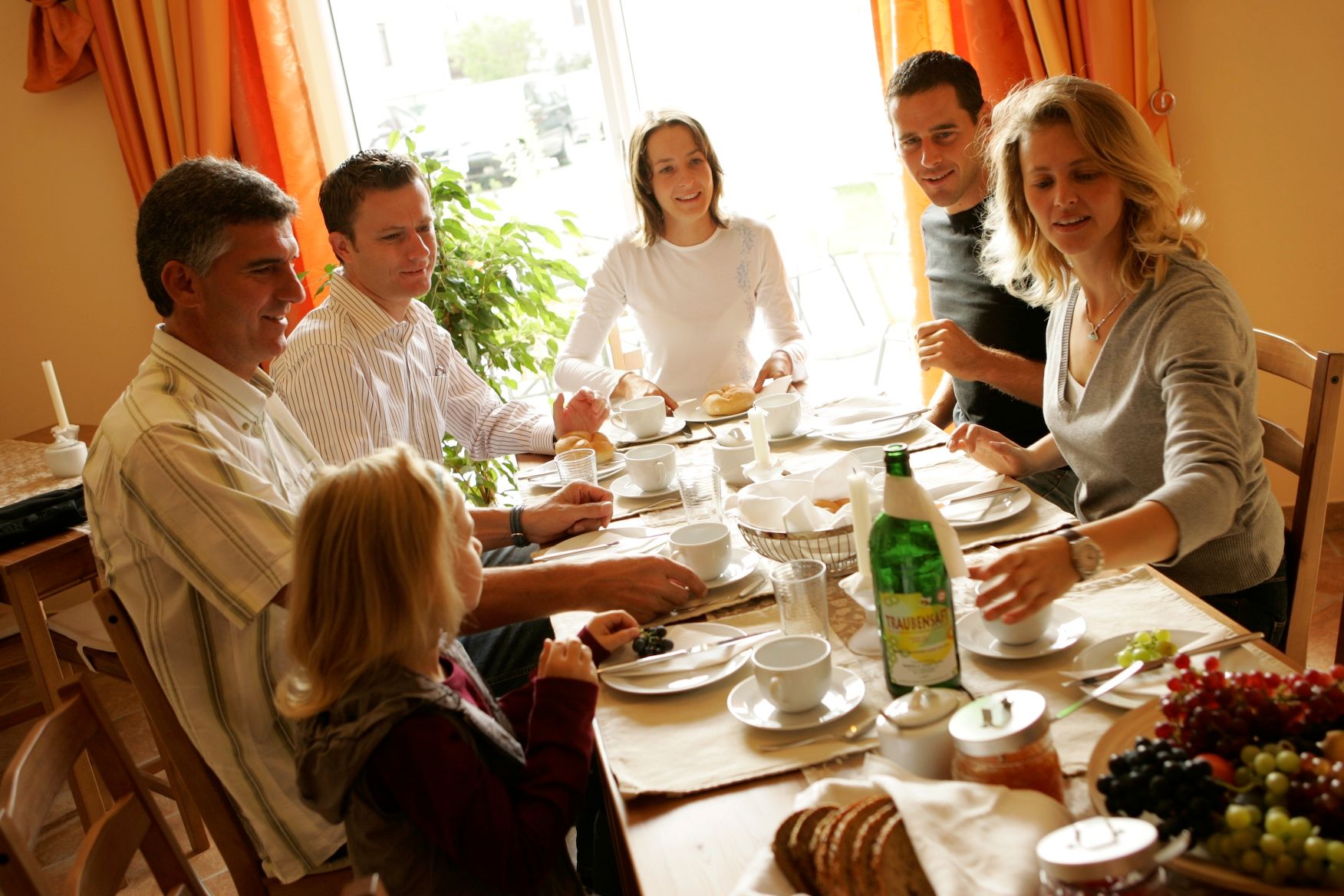 A group of people sit at a table and enjoy breakfast together.