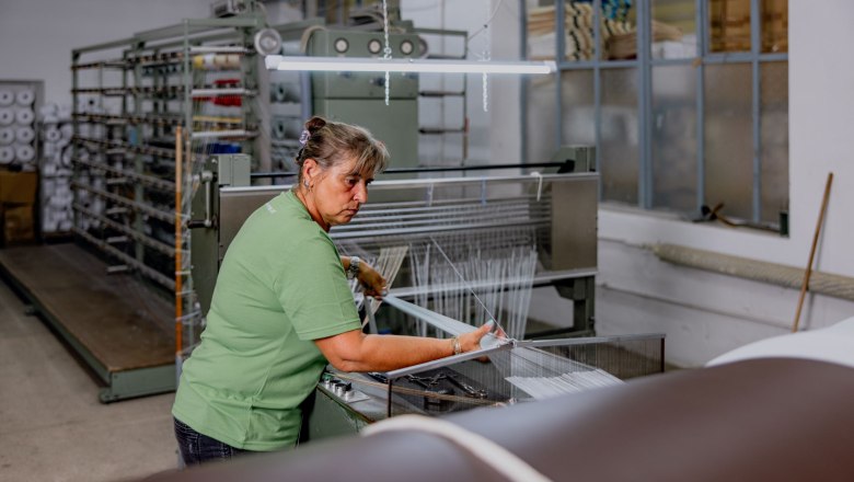 Woman working on a weaving machine in a textile factory.