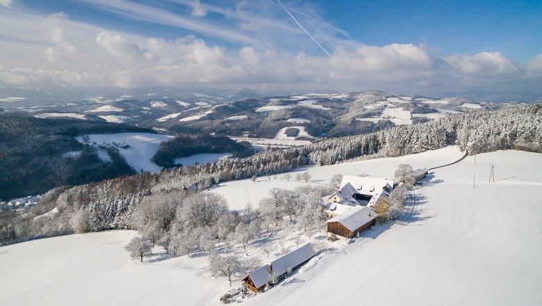 Snowy landscape with farm and hills in the background.