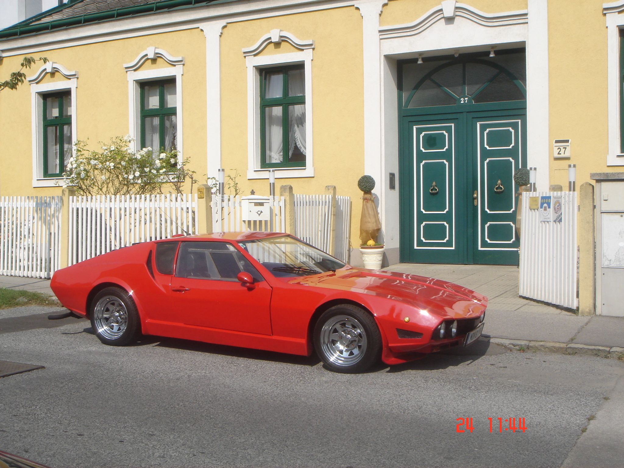 Yellow building with green door and red car.