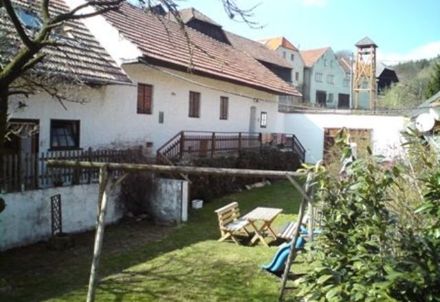 Kranzer horse farm, © Maria Kranzer A rural courtyard with white buildings, wooden table and chairs in the garden, swing and slide in the foreground.