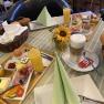 A laid breakfast table with bread rolls, cold cuts, eggs, juice and coffee in a guesthouse.