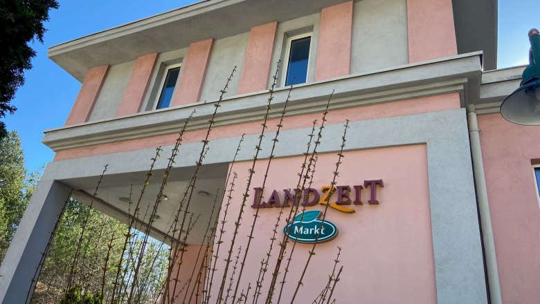 Building with pink and gray facade, lettering 'Landzeit Markt'.
