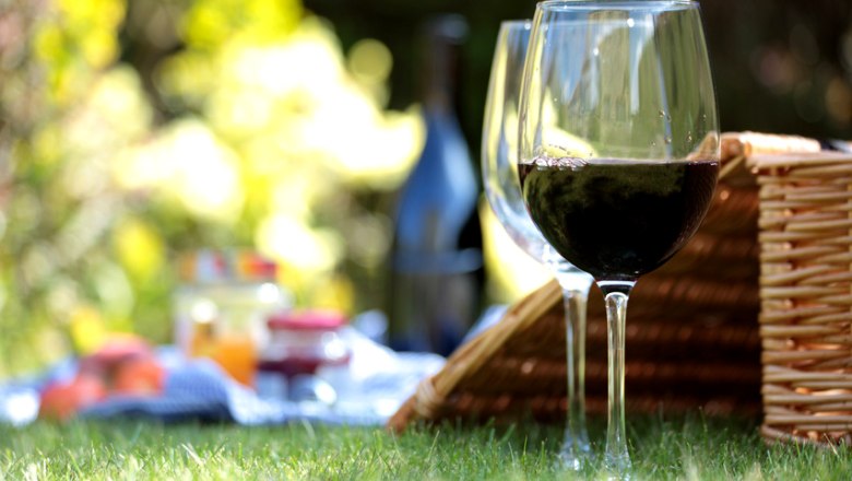 Two wine glasses and a picnic basket on a meadow.