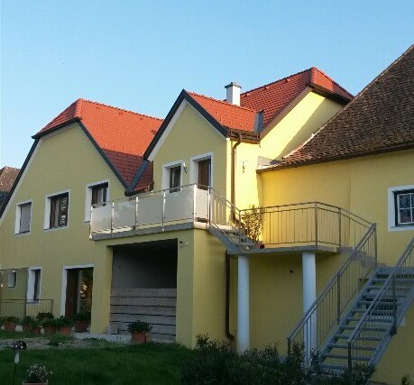 Yellow building with red roofs and external staircase.