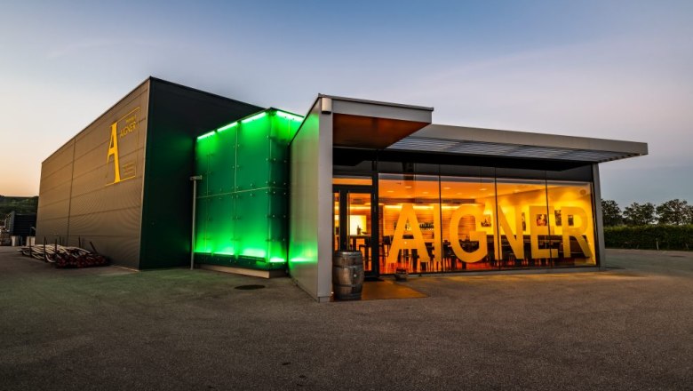 Modern winery with illuminated entrance and large 'Aigner' lettering.