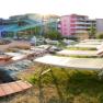 A pool area with sun loungers and a modern building in the background.
