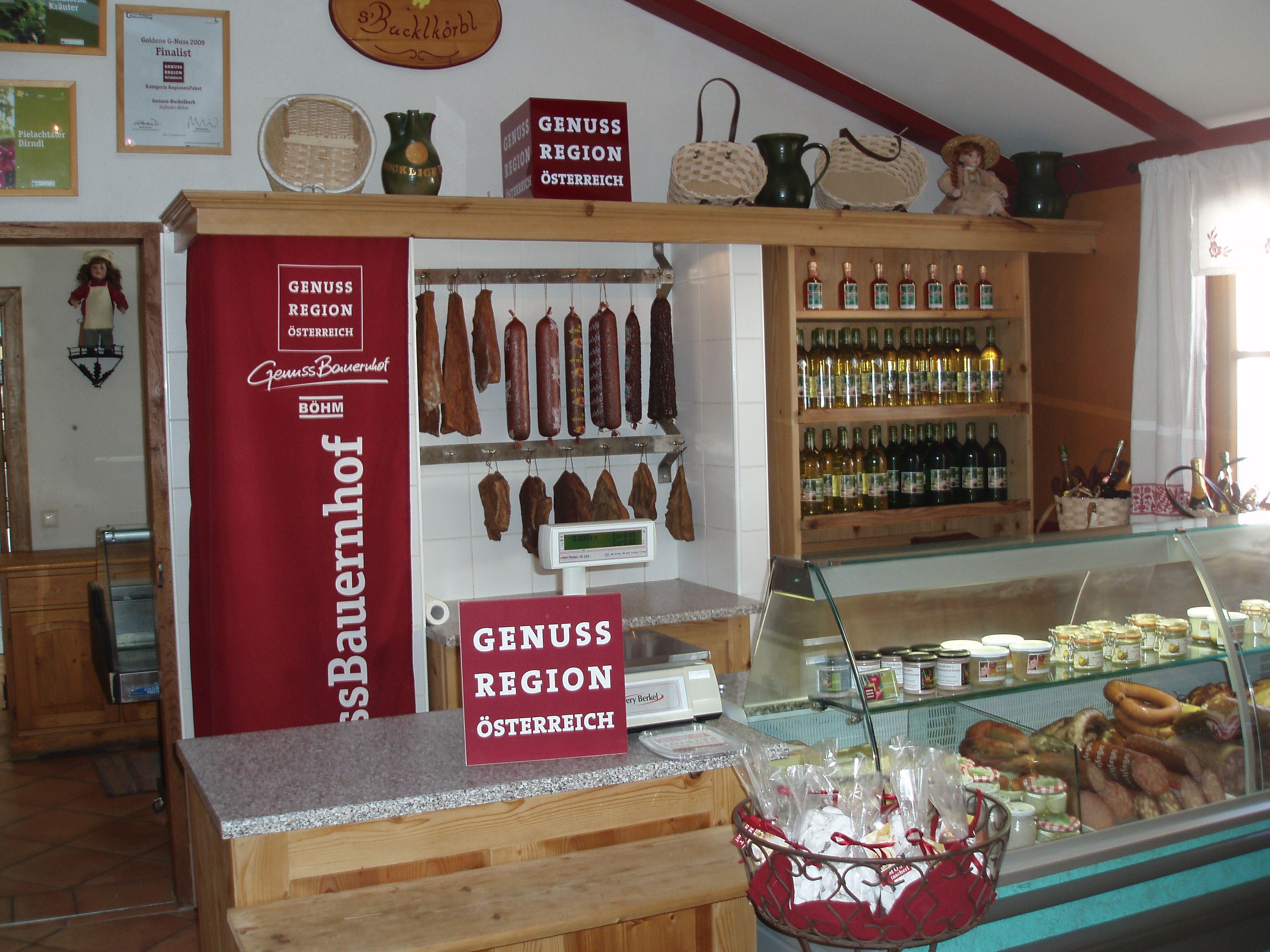 Interior view of a farm store with sausage products, bottles of wine and a refrigerated shelf.
