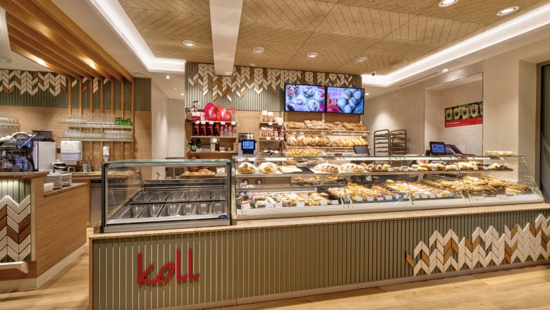 Interior view of the modern bakery with counter full of baked goods and coffee machine.