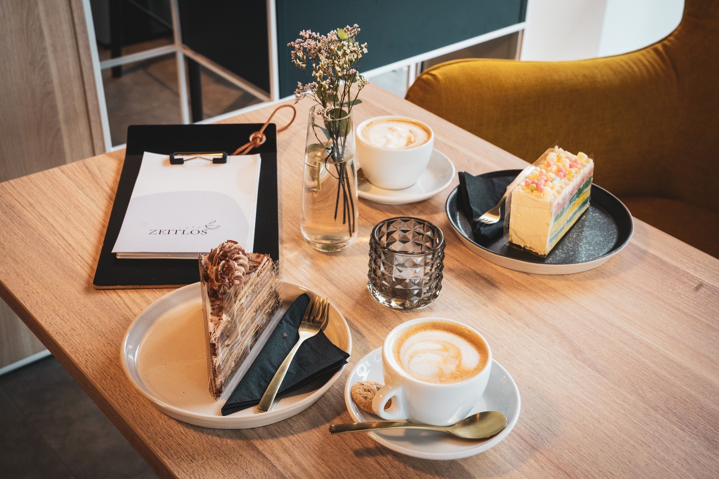 Café table with two cakes and cafés with menu and flower.