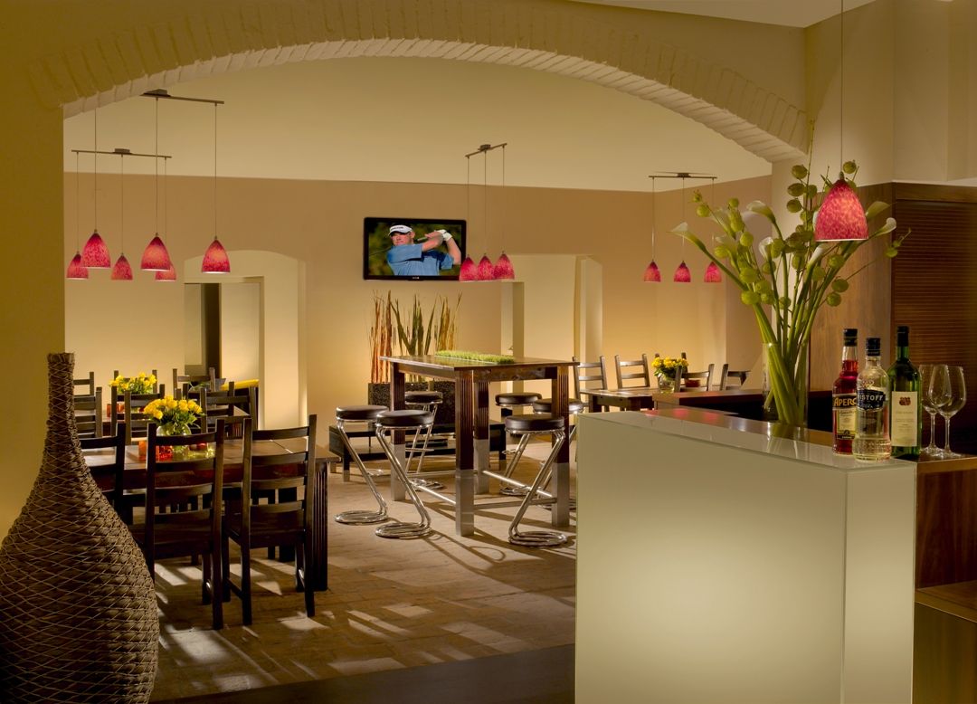 Interior view of a stylish restaurant with modern furniture and red hanging lamps.