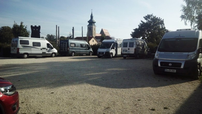 Motorhome parking space, © Sportunion Pillichsdorf Motorhome site with several parked motorhomes and a church in the background.