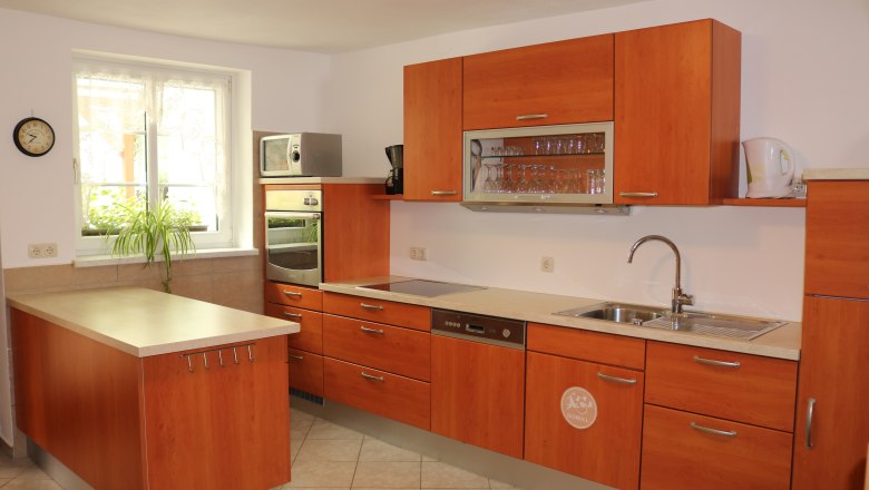 Modern kitchen with wooden cupboards, sink, stove and microwave.