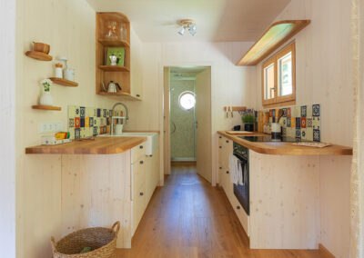 Interior view of a small, modern kitchen with wood paneling and colorful tiles.