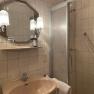A bathroom with washbasin, mirror, shower and towel.
