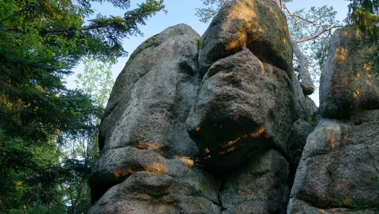 Large rock formation in the forest near St. Oswald, surrounded by trees.