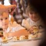 Two children watch as honey is drizzled on a dessert.