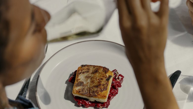 A plate with a piece of fried fish on a red garnish, photographed from above.