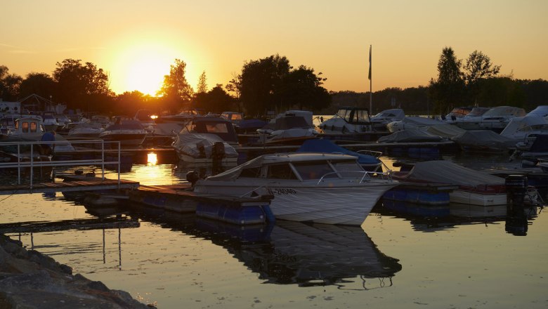 Sunset over a marina with several boats in the water.