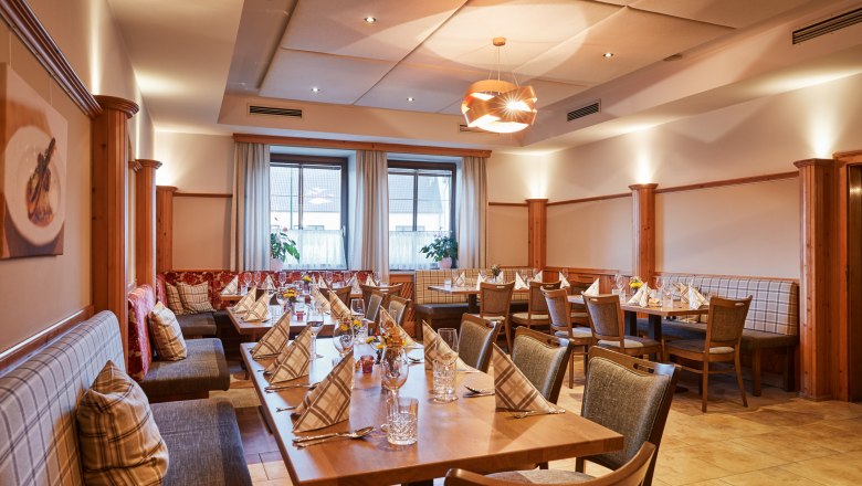 Cozy dining room with laid tables and wood paneling.