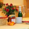 Breakfast table with bread basket, jam, champagne bottle and roses.