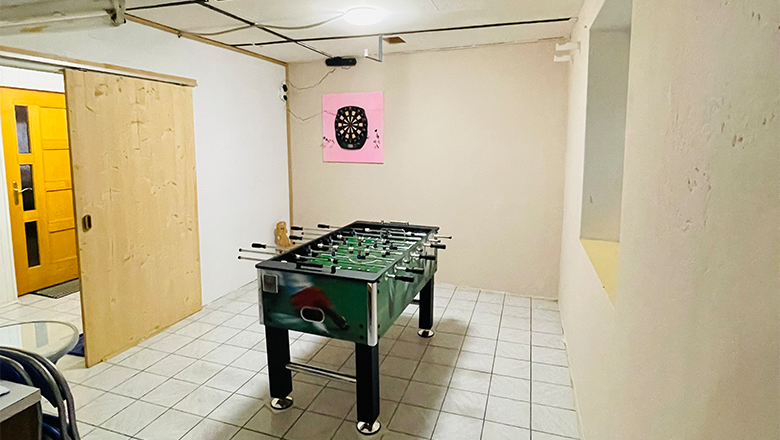 A games room with a table football table and a dartboard on the wall.